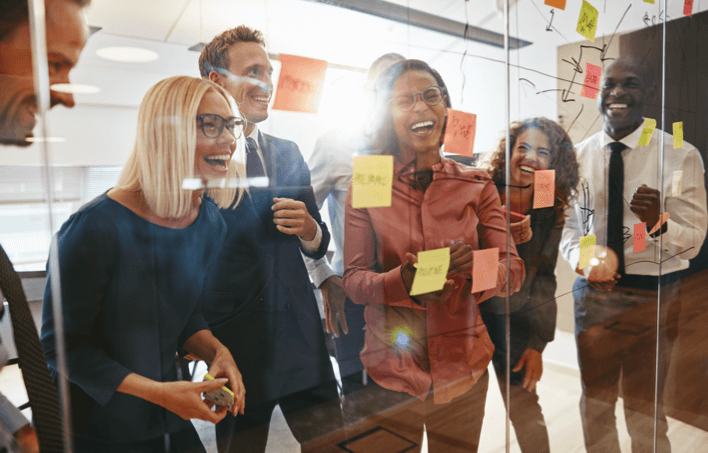 People laughing in front of glass wall with sticky notes