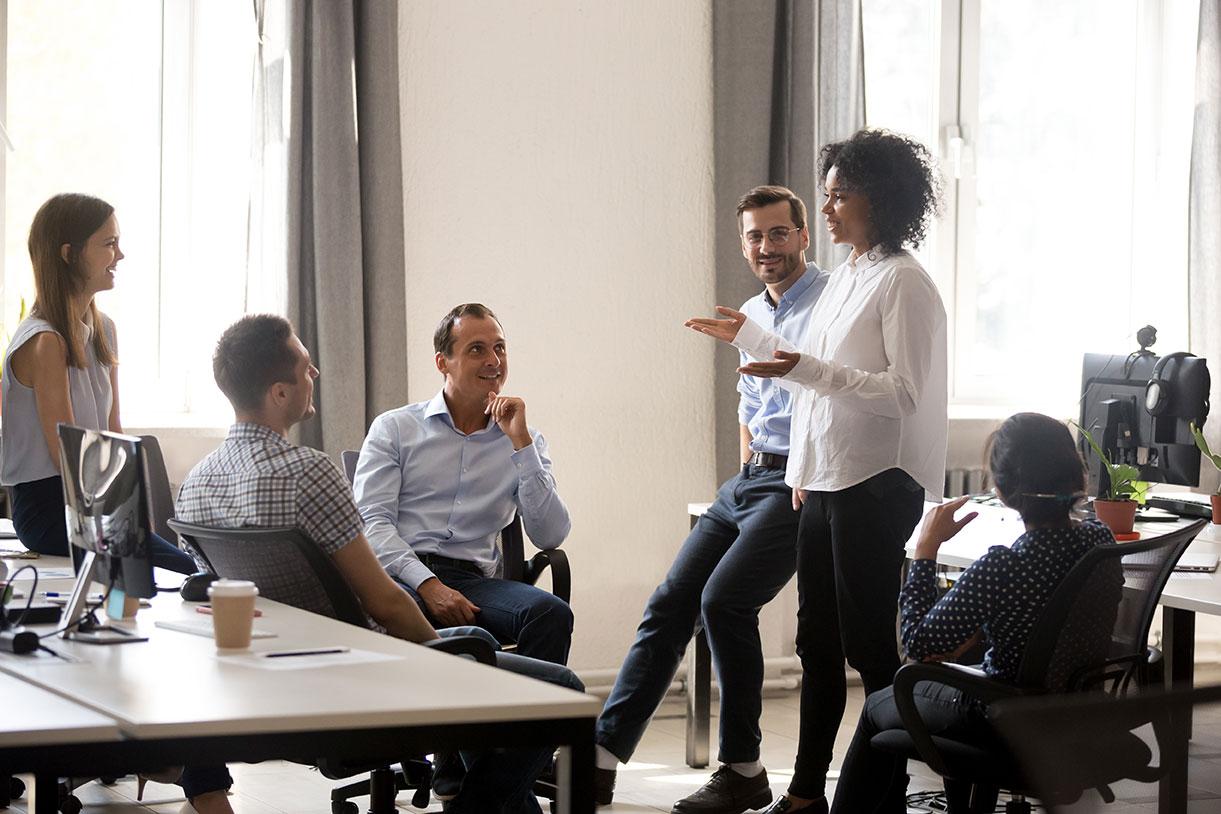 Person speaking to group gathered in an office meeting room