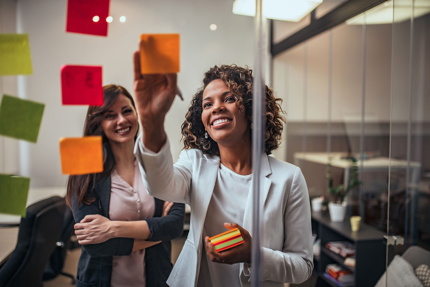 People using sticky notes in an office on a glass wall