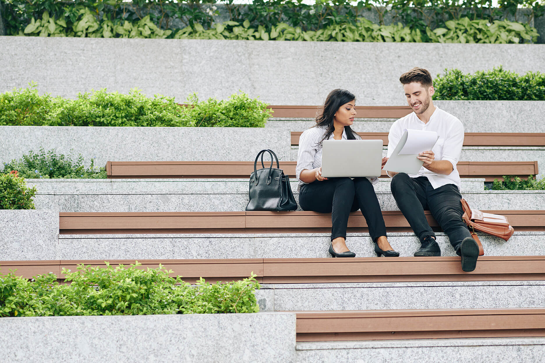 People sitting outside looking at laptop and notes